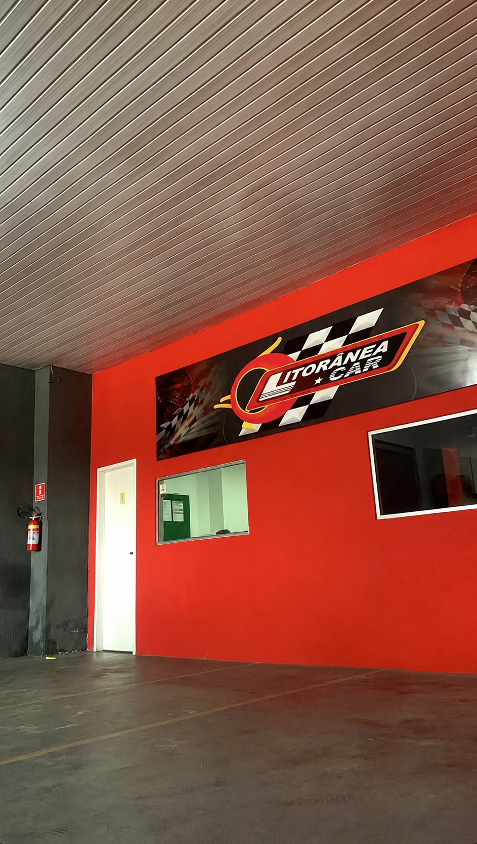 Fachada da concessionária Litorânea Car com parede vermelha e logotipo da marca